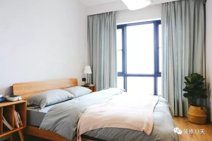 次卧白墙木地板,蓝色窗帘与床品呼应,原木家具让家更舒适
