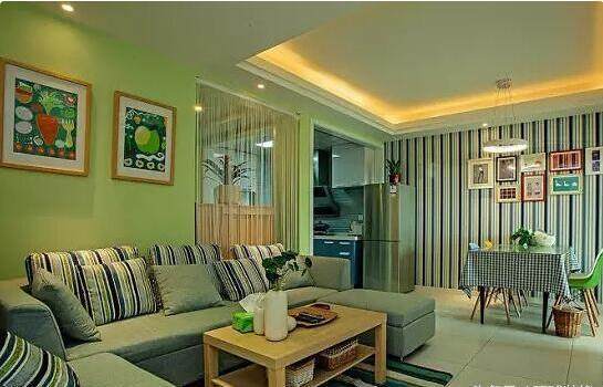 客厅后面刷了一片绿色墙面,布置要素色u型布艺沙发,看着很小清新的